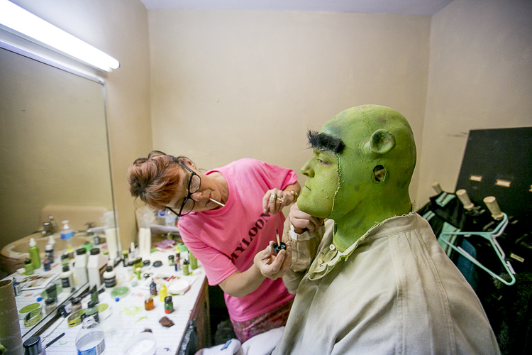 Benjamin Feliciano has his Shrek makeup applied by Park Players director, wardrober, and make-up artist Barbara Weisserman