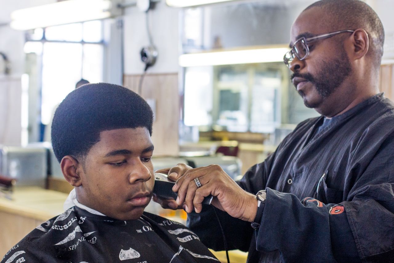Lucas, 13, getting his hair cut by Metro Detroit Barber College owner Raymond Ware