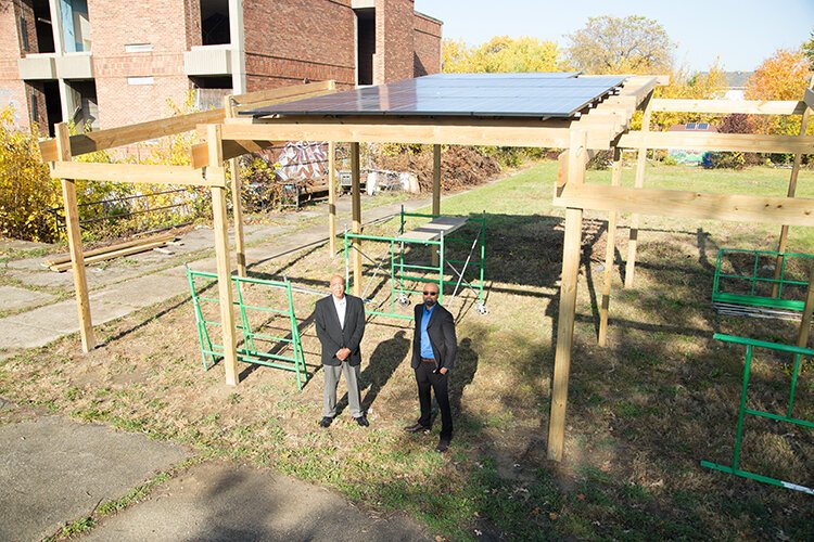 Karanja Famodou, left, and Ali Dirul pose underneath the solar panels they helped install on a pergola at Parker Village, which will be used to run an on-site cafe next year. 