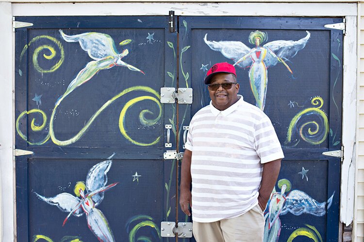 Mose Primus poses in front of a mural by Donald Hathaway, marking the way to the Yorkshire Woods "4 Angels Garden."