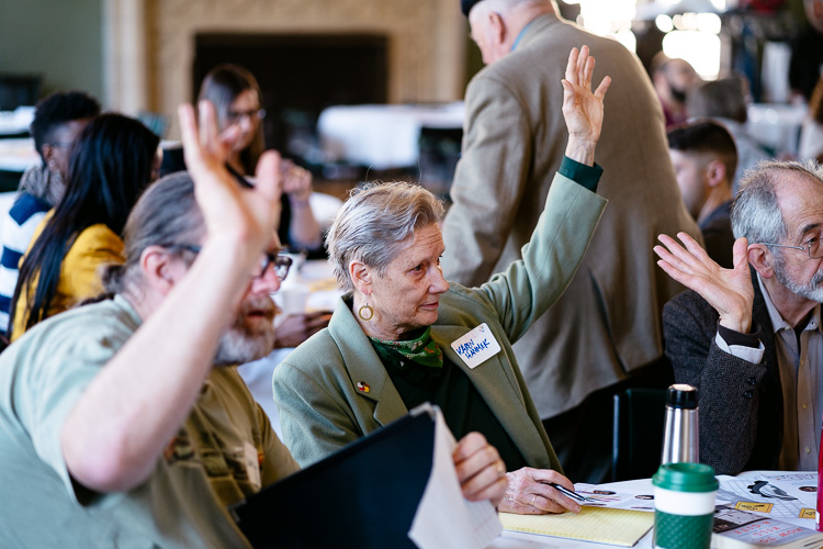 Participants raise their hands during the day's keynote address,