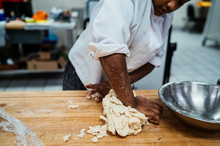 Student kneads dough in Golightly's Bakeshop