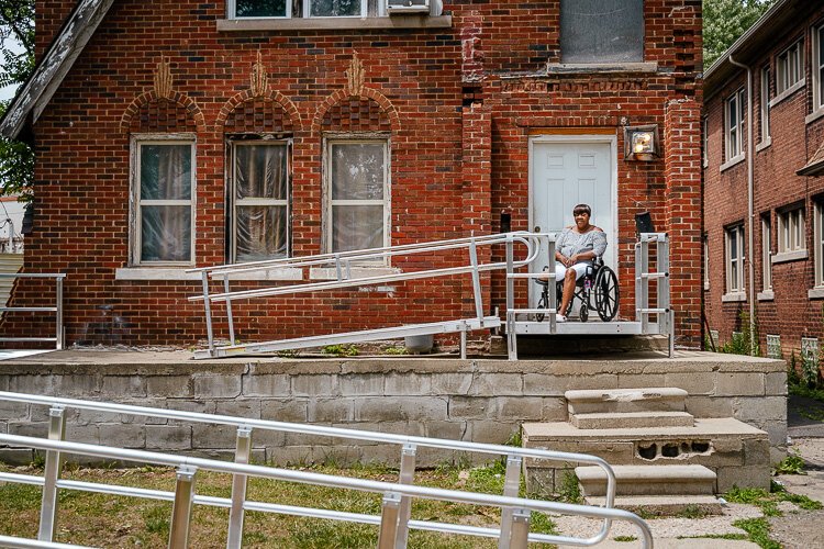 Schlann Dillard sits on her front porch looking over her new wheelchair ramp.