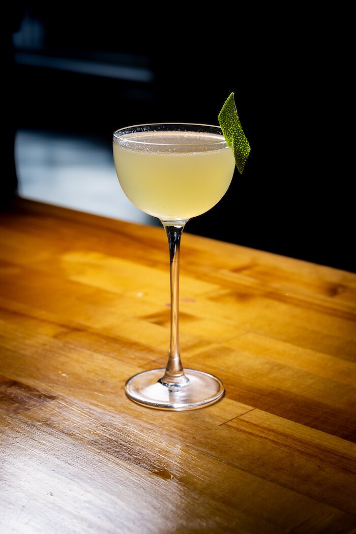 A cocktail at "Miss Eva's" draws inspiration from Sombi, a traditional dish from Senegal, which is still enjoyed throughout New Orleans today. It is made with Gran Caramino Tequila + 400 Conejos Mezcal + Passionfruit + Honey + Lime + Baking Spices. 