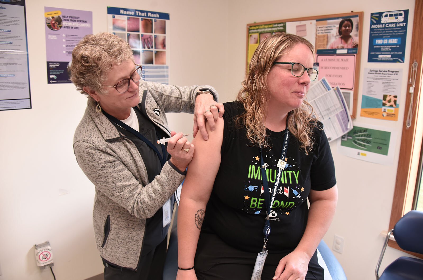 Factors like housing, education, and economic stability have as profound of an impact on health as immunizations and routine health care. Here, DHD #10's Bonnie Mellema RN administers a vaccination. 