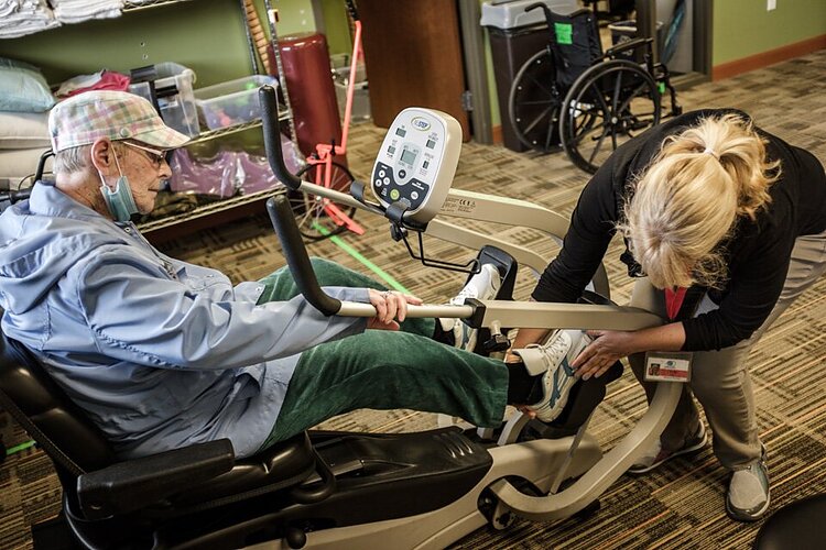 A PACE participant is helped onto an exercise bike at the LifeCircles Center in Muskegon.